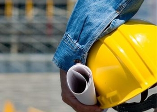 Un homme qui porte sous son bras un casque de chantier jaune