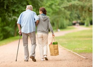 Un jeune femme aidant un homme âgé à porter son panier de courses